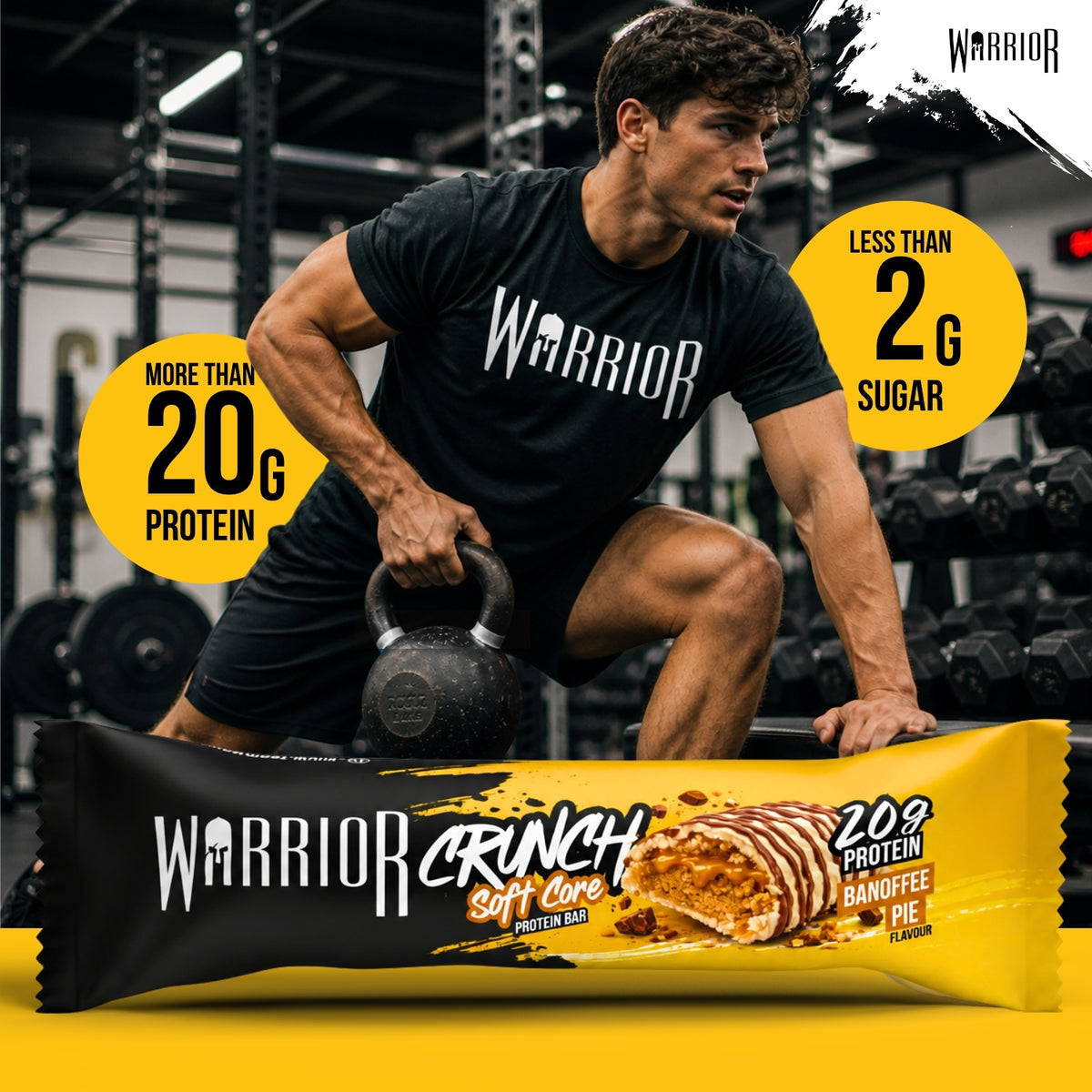 Warrior Crunch Soft Core Banoffee Pie protein bar wrapper on a gym floor, with a man in Warrior kit holding a kettlebell behind it and callouts for more than 20g protein and less than 2g sugar.