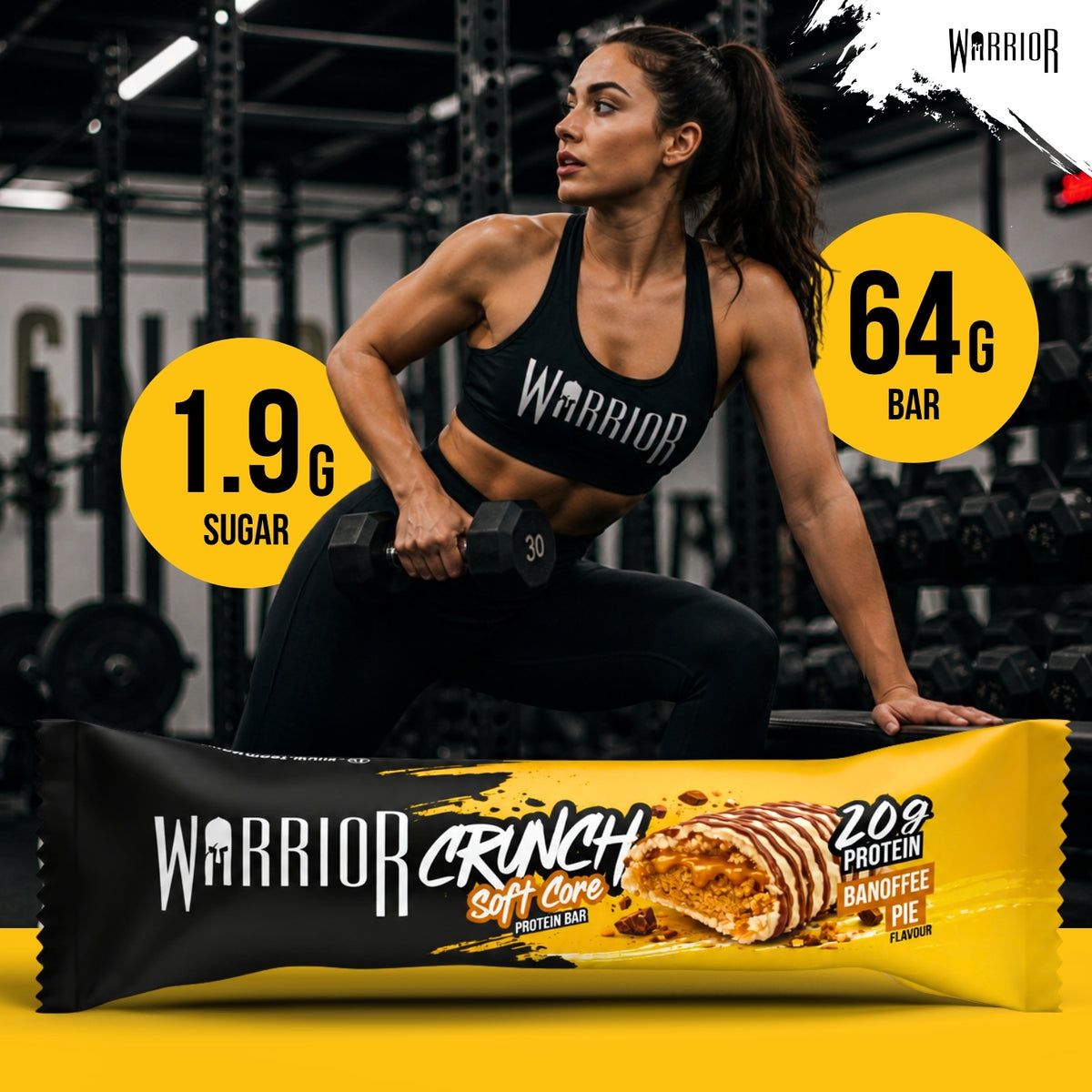 Warrior Crunch Soft Core Banoffee Pie protein bar wrapper on a gym floor, with a woman in Warrior kit holding a dumbbell behind it and callouts for 1.9g sugar and a 64g bar.