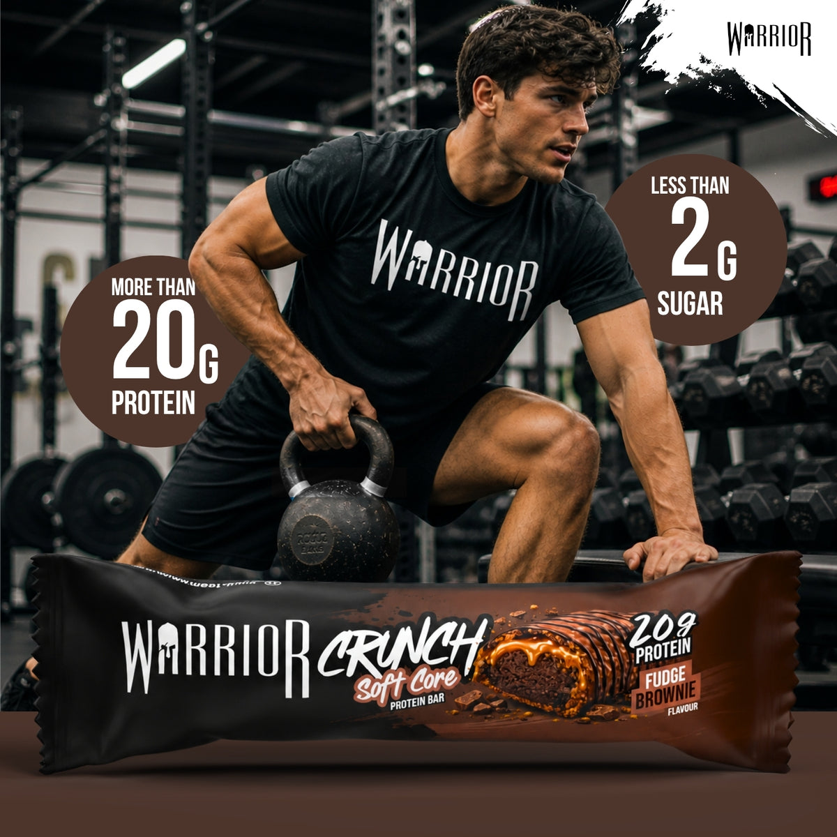Warrior Crunch Soft Core Fudge Brownie protein bar wrapper on a gym floor, with a man in Warrior kit holding a kettlebell behind it and callouts for more than 20g protein and less than 2g sugar.
