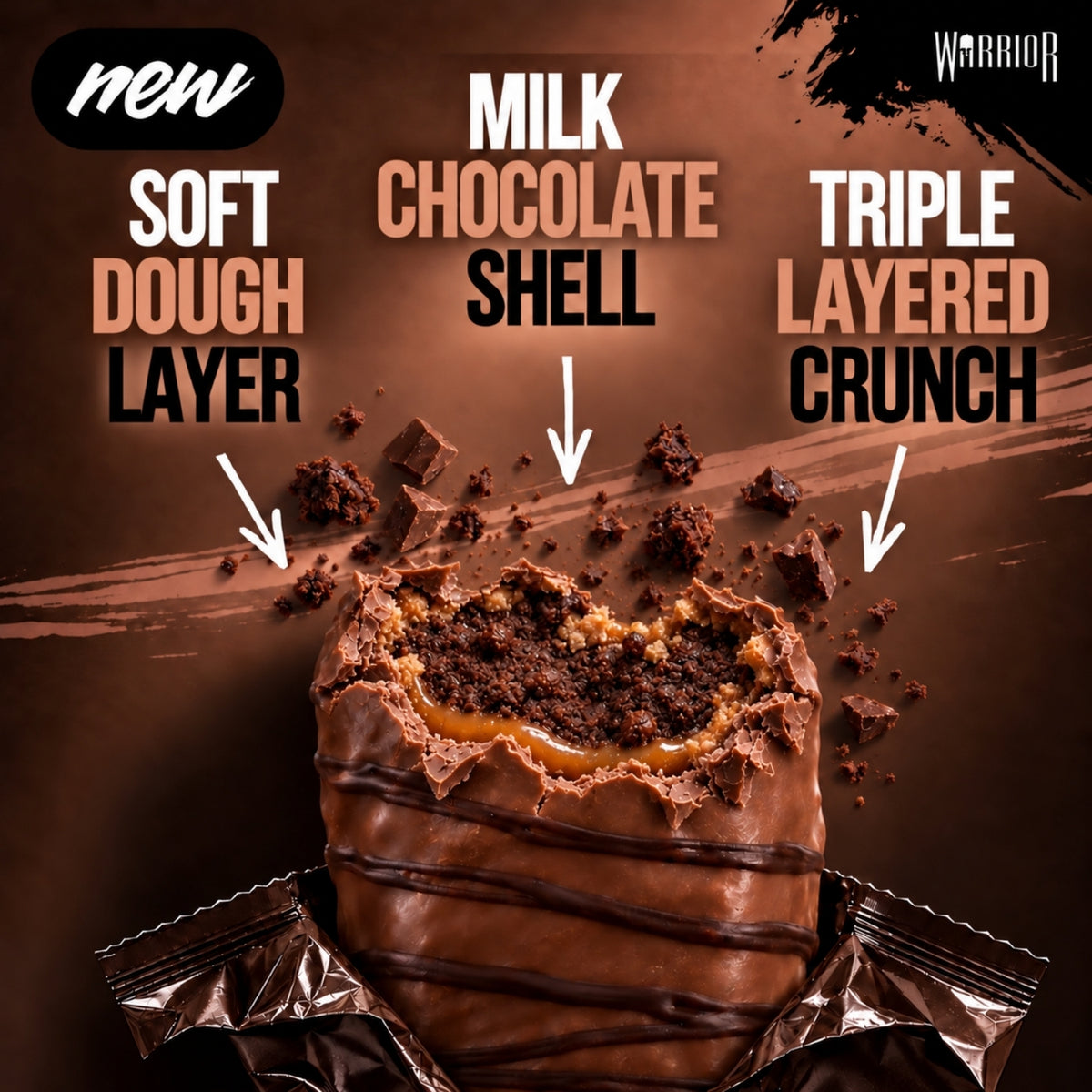 Warrior Crunch Fudge Brownie protein bar, cut open to show the soft dough layer, milk chocolate shell and triple-layered crunch with a caramel centre, wrapper partially peeled back on a dark brown background with chocolate crumb pieces.