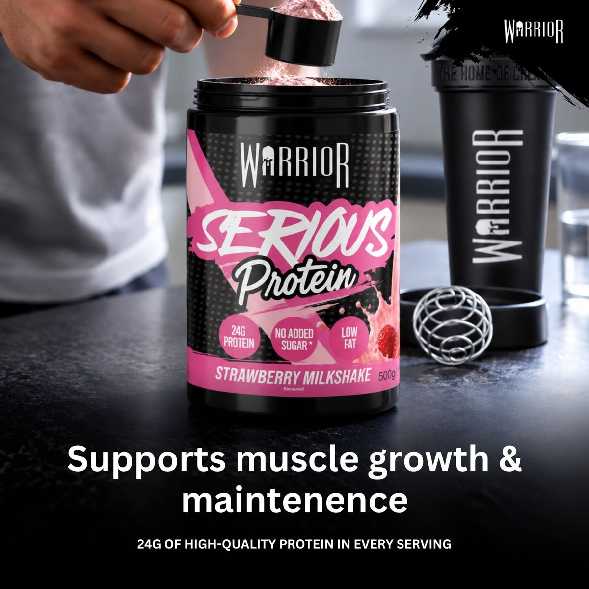 A person's hand is shown adding pink powder from a scoop into a black canister of Warrior Serious Protein Strawberry Milkshake. A black shaker bottle and a metal mixing ball sit on the counter next to the tub, with promotional text at the bottom.