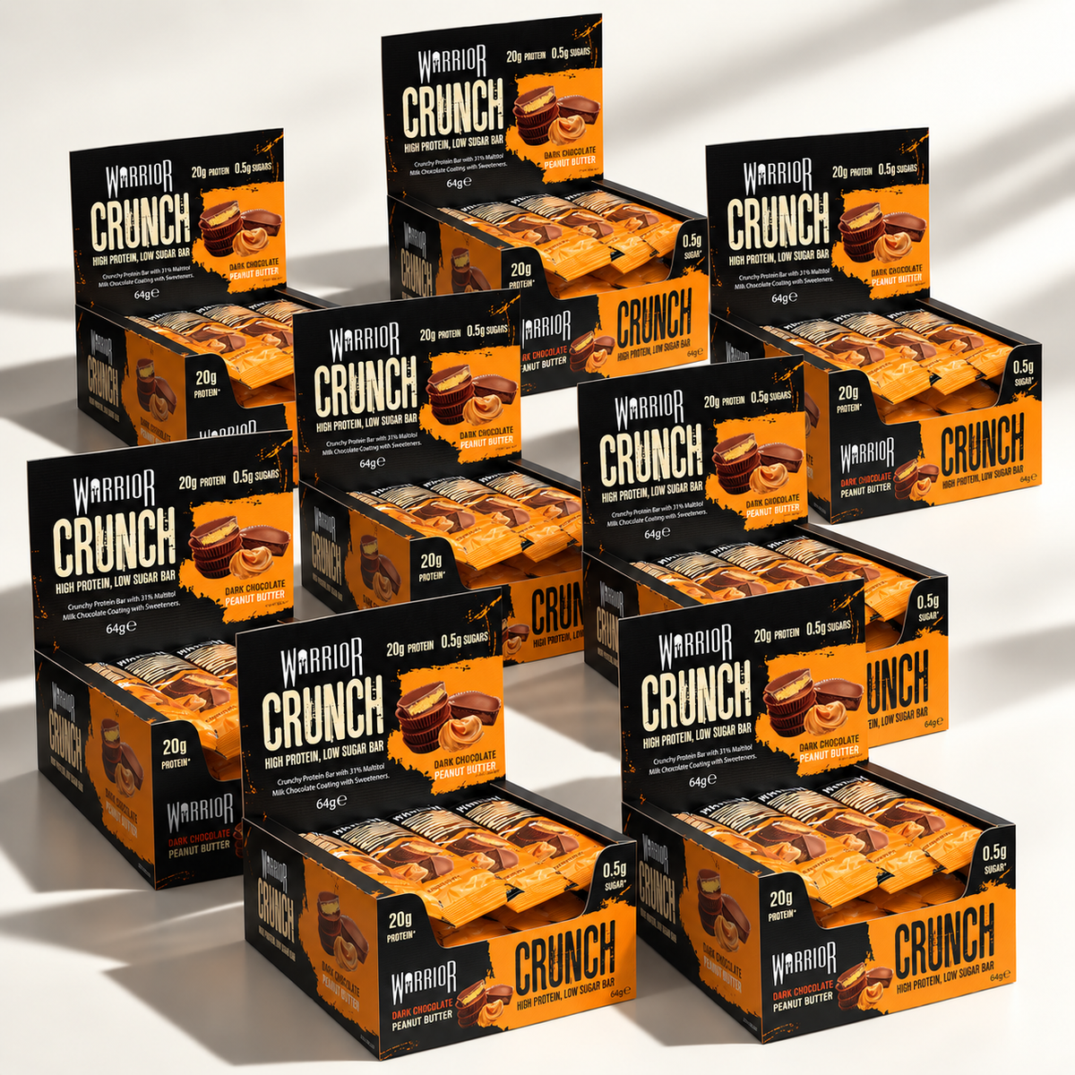 Eight Warrior CRUNCH Dark Chocolate Peanut protein bar display boxes arranged in an overlapping cluster on an off-white background, with red and black packaging and dramatic studio lighting.